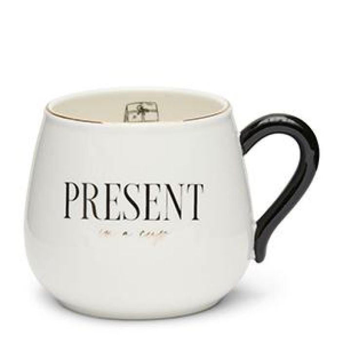 Present in a Cup Mug Kahvikuppi mustalla tekstilla ja kultakoristeilla.